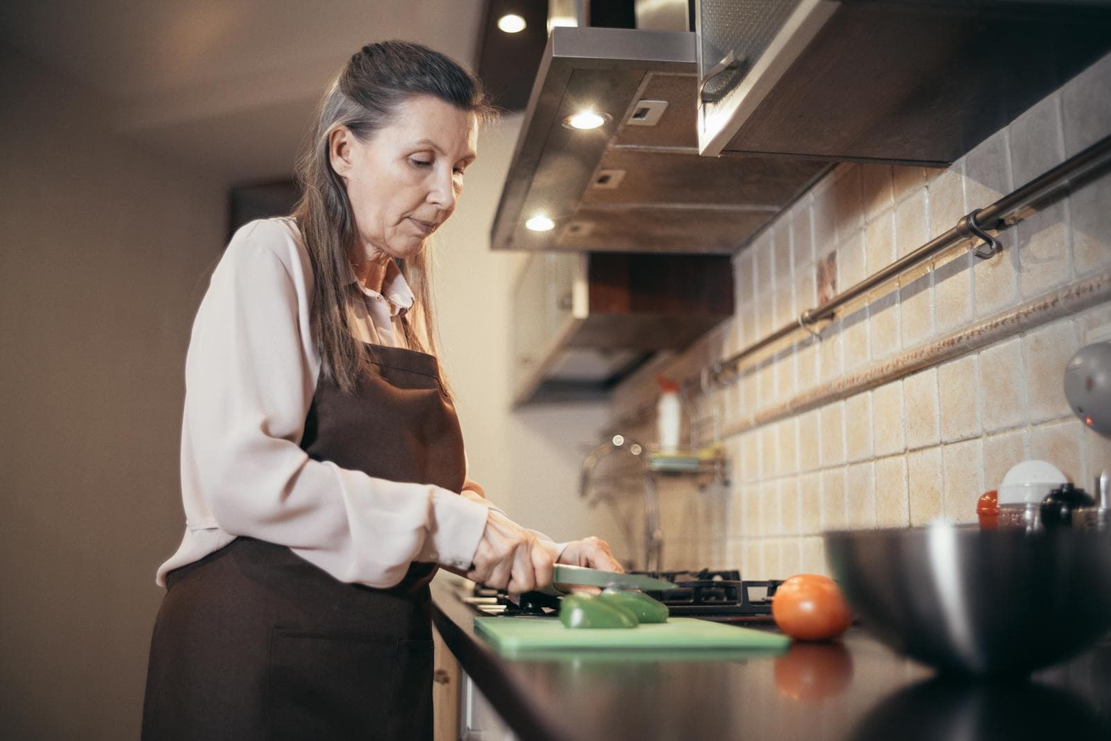 An older woman comfortably preparing food at a kitchen counter
